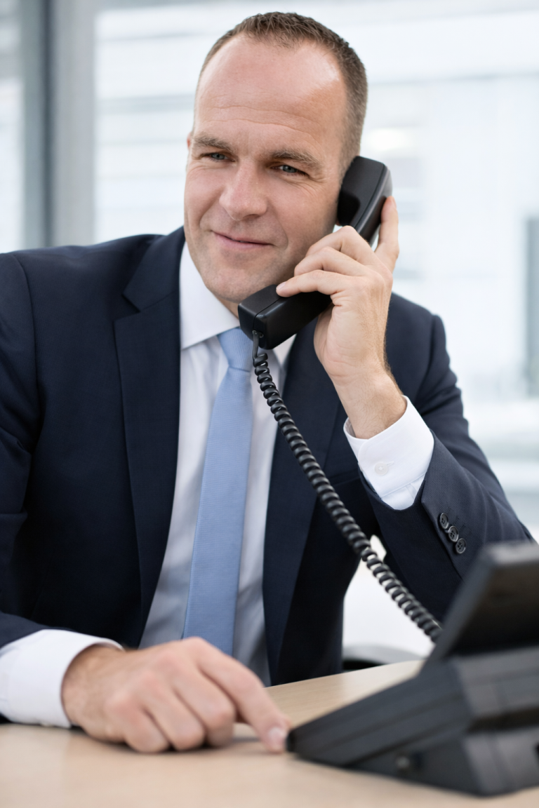 Geschäftsmann im Anzug, der am Telefon spricht, mit einem seriösen Lächeln.