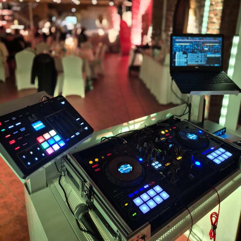 DJ-Setup mit Mixer und Laptop, umgeben von einem eleganten Event-Ambiente.