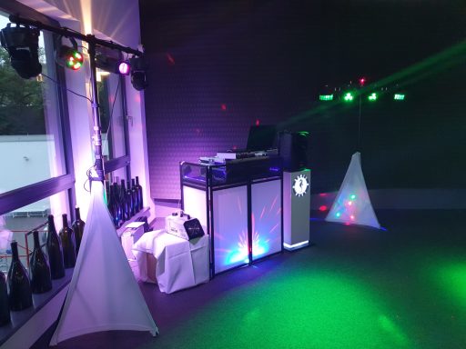 DJ-Pult mit Beleuchtung und Dekoration in einem Veranstaltungssaal.