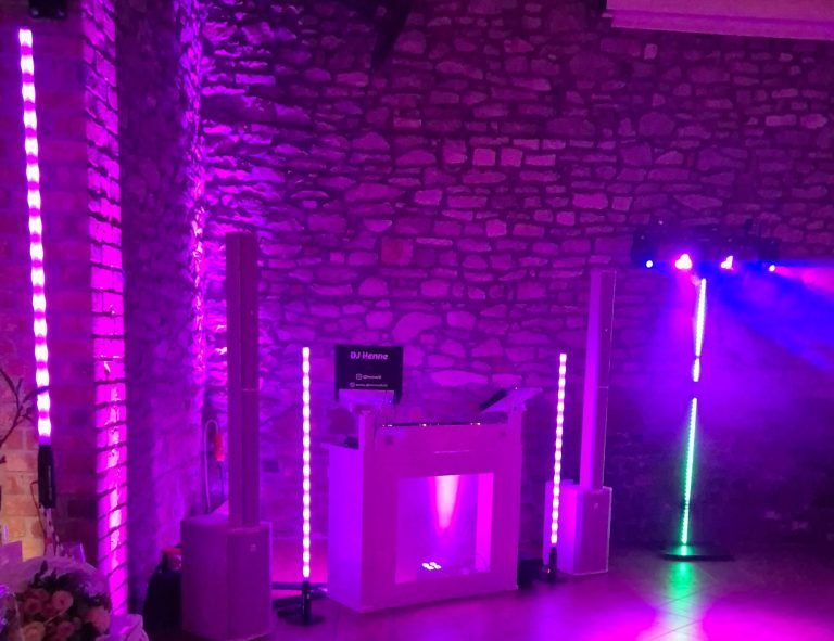 Bunte Lichter und eine DJ-Station in einem festlichen, gemauerten Veranstaltungsraum.